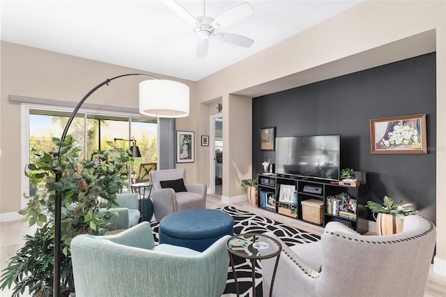 living area featuring baseboards and ceiling fan