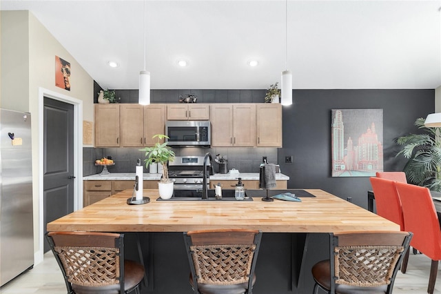 kitchen featuring a sink, stainless steel appliances, a breakfast bar area, decorative backsplash, and hanging light fixtures