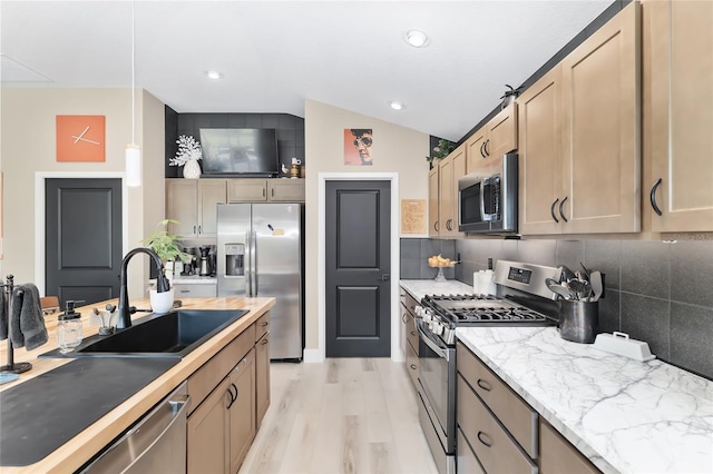 kitchen with tasteful backsplash, light wood finished floors, stainless steel appliances, and a sink