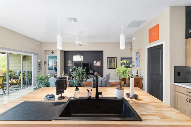 kitchen featuring visible vents, wooden counters, open floor plan, and a sink