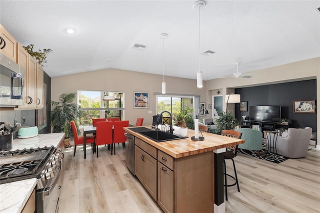 kitchen with butcher block counters, visible vents, stainless steel appliances, and a sink