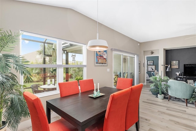 dining room featuring light wood-type flooring and vaulted ceiling