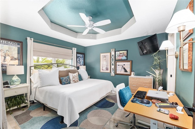 bedroom featuring baseboards, a raised ceiling, and ceiling fan