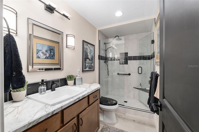 bathroom featuring vanity, a shower stall, and toilet