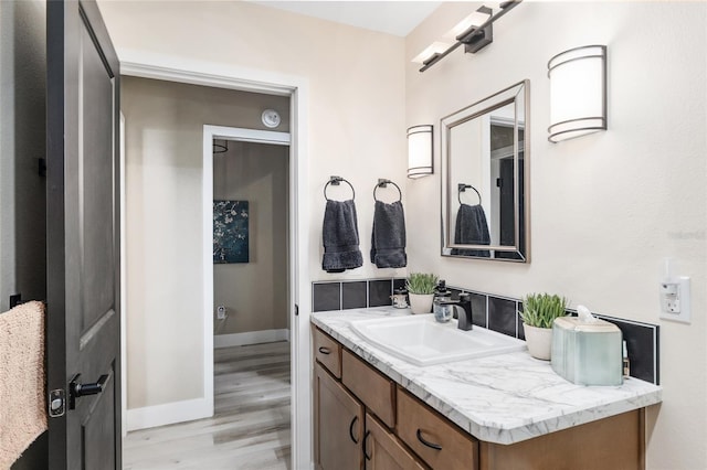 bathroom with vanity, wood finished floors, and baseboards