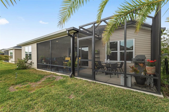 back of property with a yard, a patio, and glass enclosure