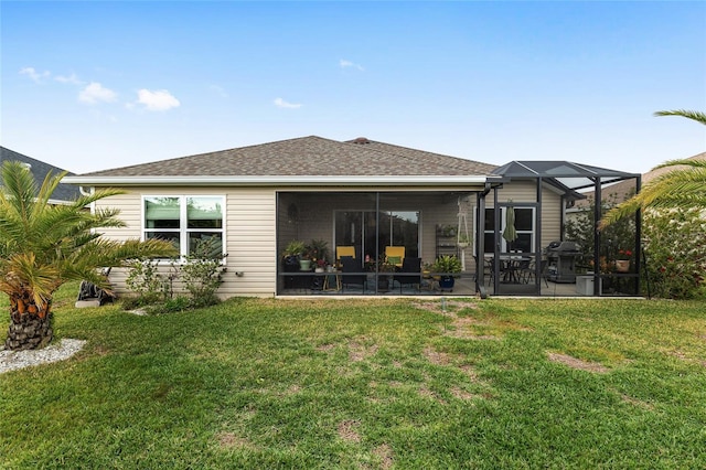 rear view of house with a patio area, a lawn, and a shingled roof