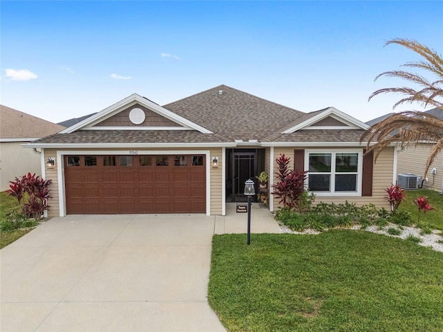 ranch-style home with concrete driveway, a front yard, roof with shingles, central AC unit, and a garage