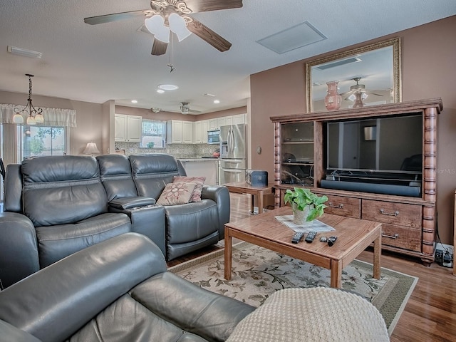 living area featuring wood finished floors, a ceiling fan, and visible vents