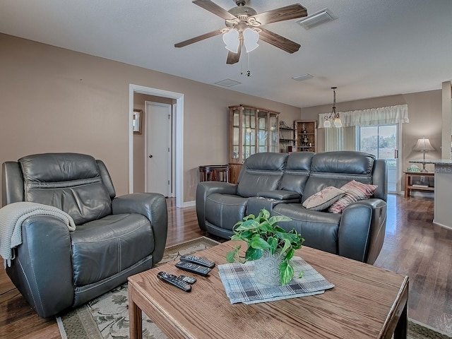 living area featuring visible vents, baseboards, a ceiling fan, and wood finished floors