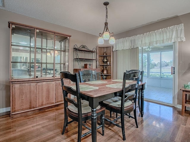 dining room with light wood-type flooring, baseboards, and a textured ceiling