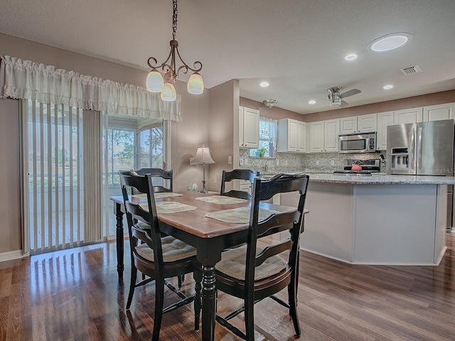 dining area with an inviting chandelier, dark wood-style floors, visible vents, and a wealth of natural light