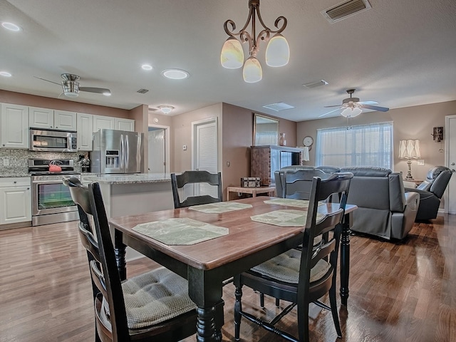 dining space with visible vents, wood finished floors, and a ceiling fan