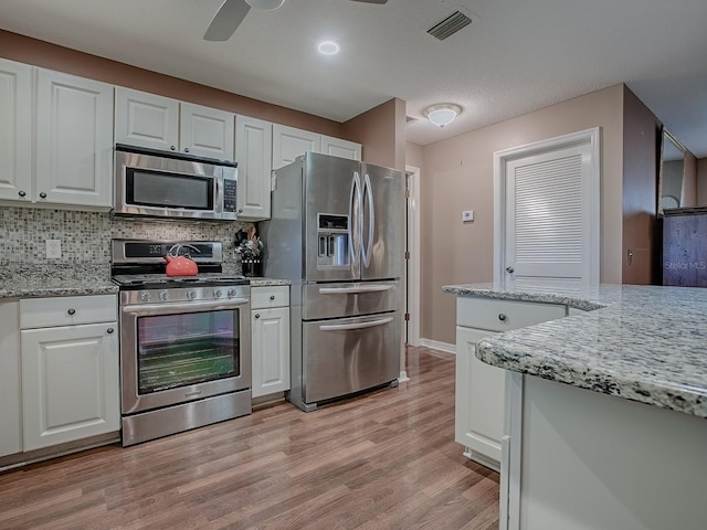 kitchen featuring a ceiling fan, visible vents, decorative backsplash, white cabinets, and appliances with stainless steel finishes