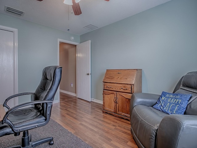 office space with light wood-style flooring, a ceiling fan, visible vents, and baseboards