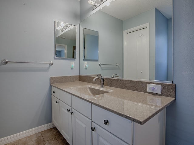 bathroom with baseboards, vanity, and tile patterned flooring