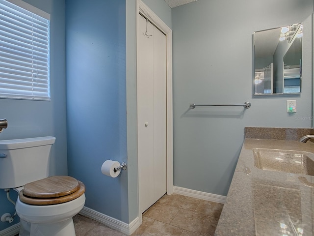 bathroom with baseboards, toilet, vanity, and tile patterned flooring