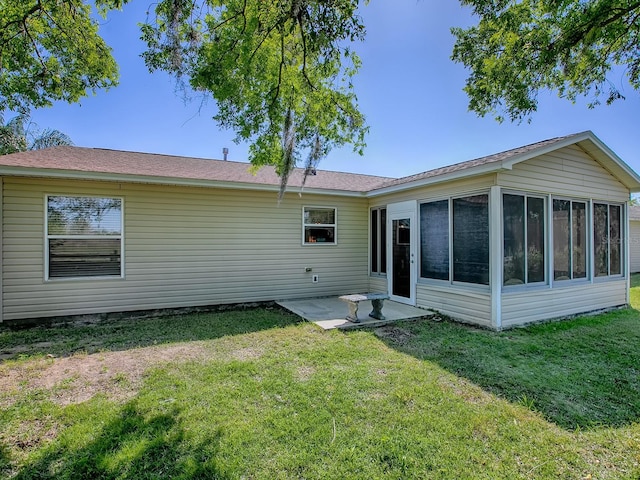 rear view of house featuring a patio, a lawn, and a sunroom