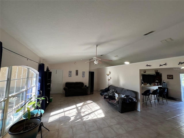 living area featuring lofted ceiling, plenty of natural light, visible vents, and ceiling fan