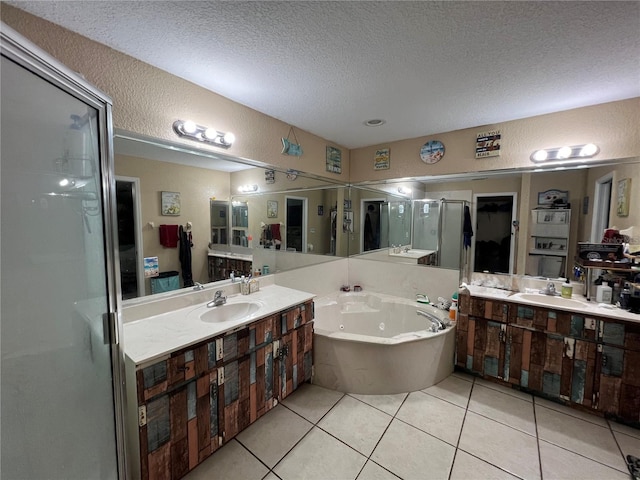 bathroom with tile patterned floors, a shower stall, a textured ceiling, and a sink