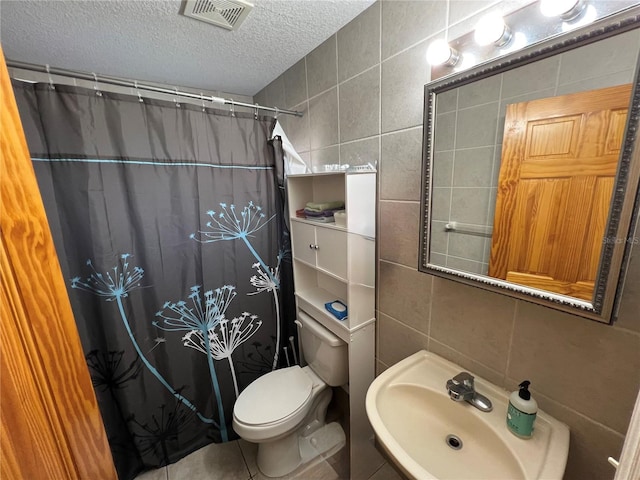 full bathroom with visible vents, a sink, a textured ceiling, a shower with shower curtain, and tile walls