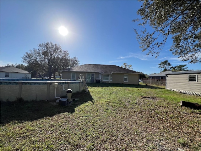 rear view of house with a yard and an outdoor pool