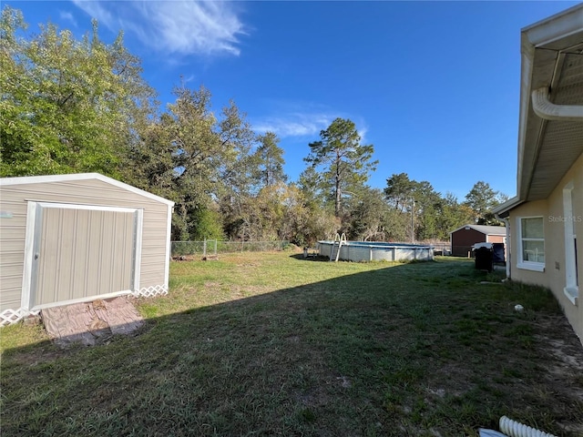 view of yard with an outdoor pool, fence, an outdoor structure, and a shed