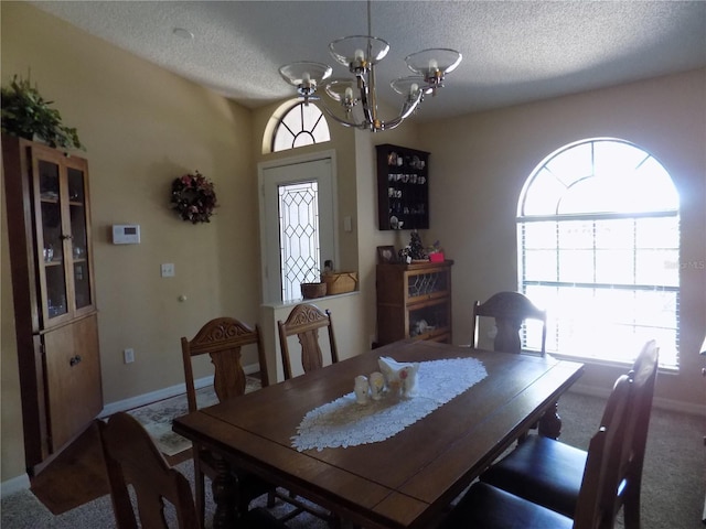 dining space with an inviting chandelier, baseboards, carpet floors, and a textured ceiling