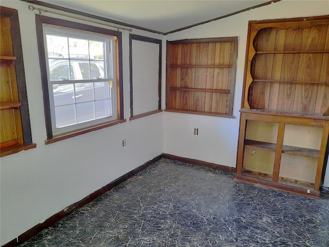 empty room featuring lofted ceiling and baseboards