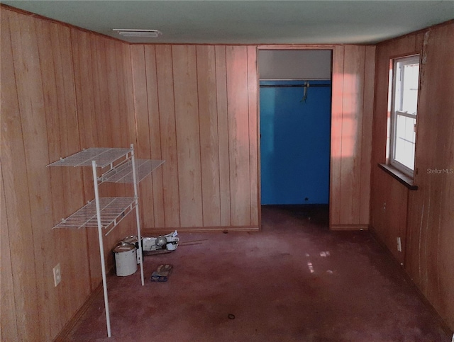 unfurnished bedroom with visible vents, carpet floors, and wooden walls