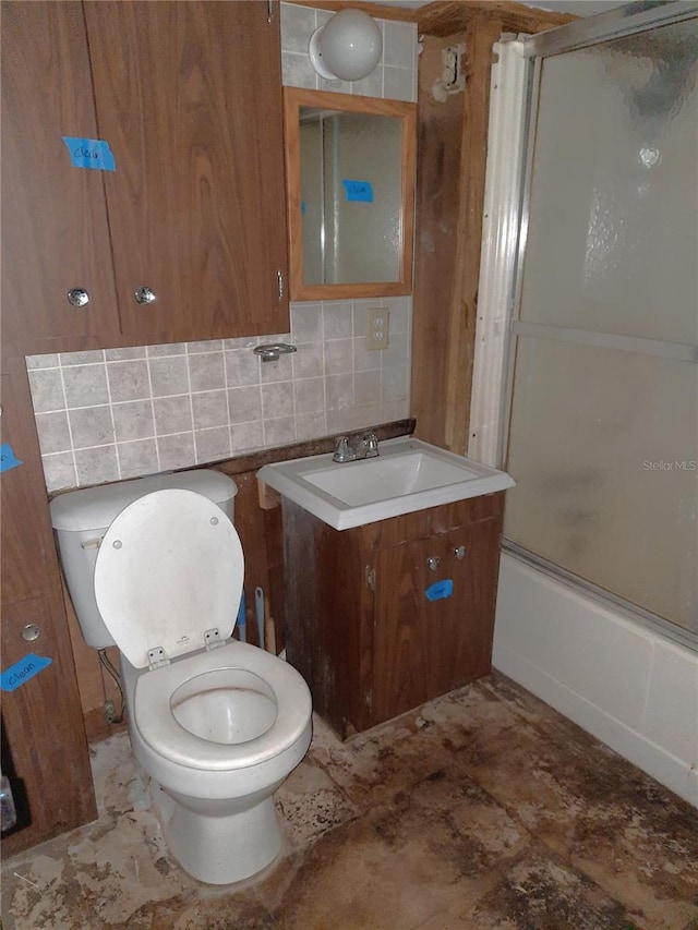 bathroom featuring backsplash, vanity, toilet, and bath / shower combo with glass door