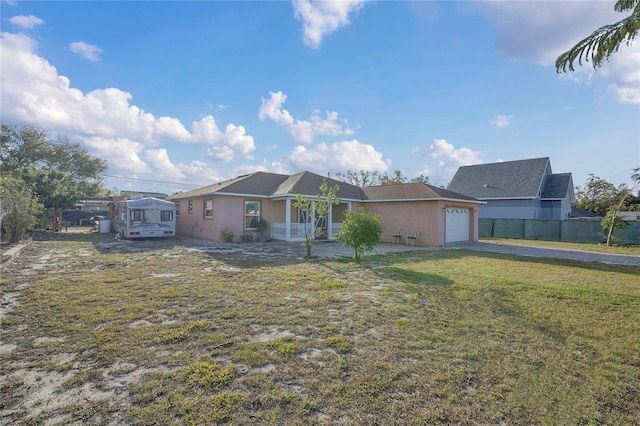 view of front of house featuring a front yard, fence, driveway, stucco siding, and a garage