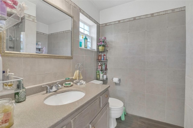 bathroom featuring toilet, tile walls, and vanity