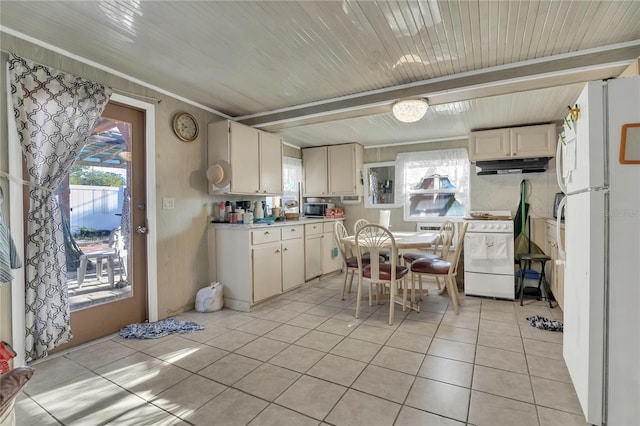 kitchen featuring a healthy amount of sunlight, under cabinet range hood, light countertops, light tile patterned flooring, and white appliances