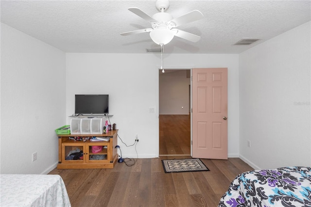 bedroom with baseboards, visible vents, a textured ceiling, and wood finished floors