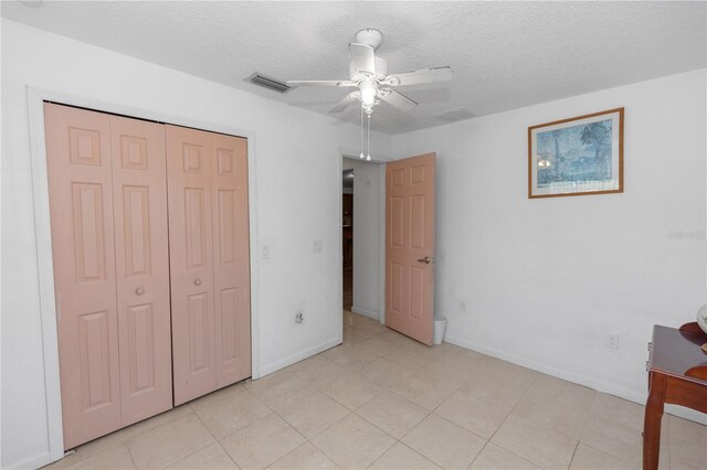 unfurnished bedroom featuring a closet, a textured ceiling, visible vents, baseboards, and ceiling fan