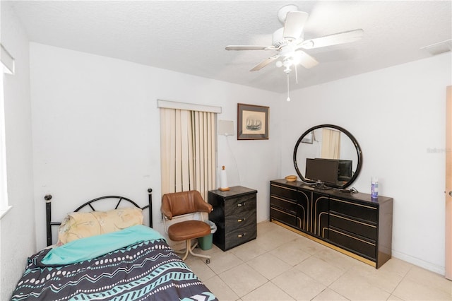 bedroom featuring tile patterned floors, ceiling fan, and a textured ceiling