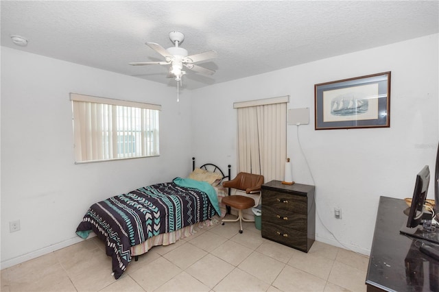 bedroom with ceiling fan, a textured ceiling, baseboards, and light tile patterned floors