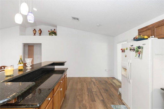 kitchen featuring lofted ceiling, brown cabinetry, visible vents, white refrigerator with ice dispenser, and dark wood-type flooring
