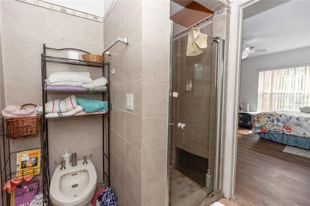 bathroom with tile walls, ceiling fan, a shower stall, a bidet, and wood finished floors