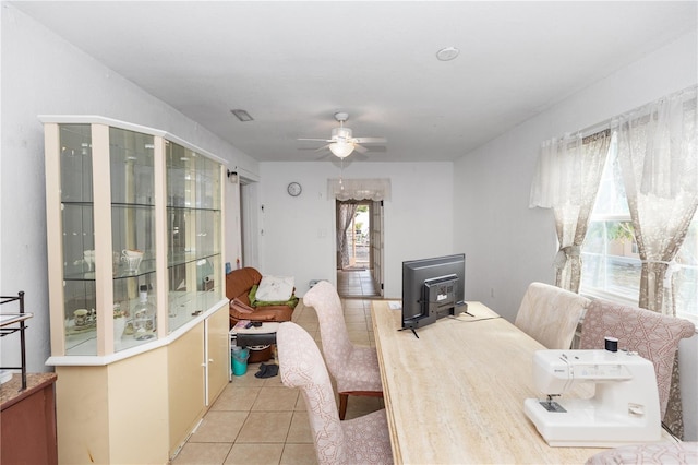 dining area with a wood stove, ceiling fan, and light tile patterned flooring