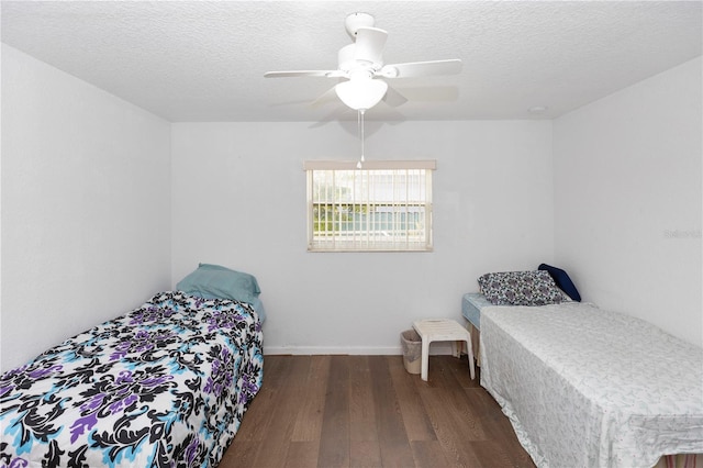 bedroom featuring baseboards, ceiling fan, a textured ceiling, and wood finished floors