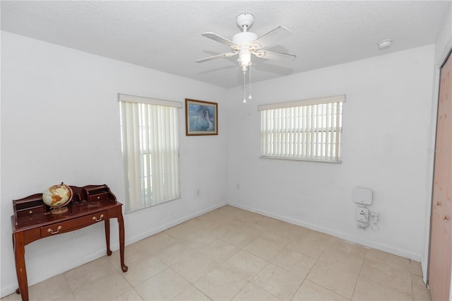 unfurnished room with a textured ceiling, baseboards, and ceiling fan