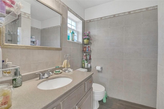 bathroom featuring toilet, tile walls, vanity, and wood finished floors