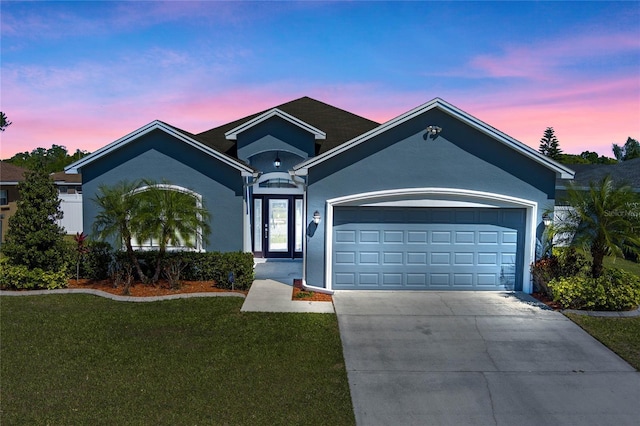 single story home with stucco siding, a lawn, a garage, and driveway