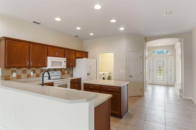 3341 Winchester Estates Cir, Lakeland, FL 33810 - kitchen with white appliances, washing machine and dryer, light countertops, arched walkways, and light tile patterned floors