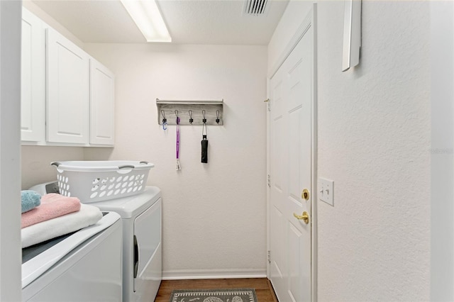 laundry room with visible vents, dark wood finished floors, cabinet space, baseboards, and washing machine and clothes dryer