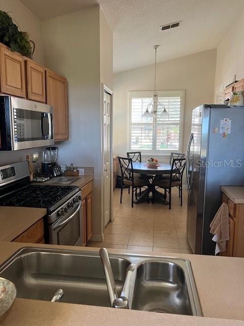 kitchen featuring light tile patterned floors, pendant lighting, lofted ceiling, appliances with stainless steel finishes, and visible vents