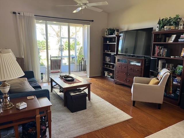 living room featuring lofted ceiling, a ceiling fan, and wood finished floors