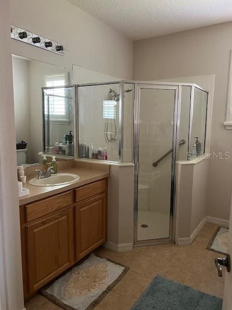 bathroom with a shower stall, a textured ceiling, tile patterned floors, and vanity